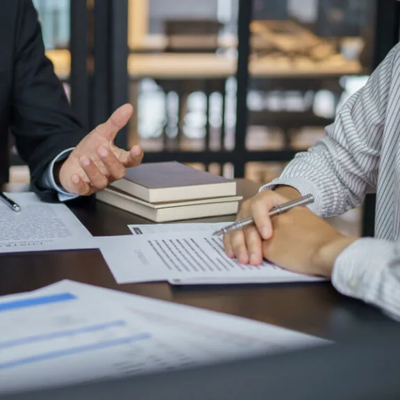 two people sitting at a table discussing paperwork